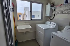 A laundry room with a washing machine, dryer, and a sink. - Moderno, Seguro, Cerca Aeropuerto SDQ, Gym, 2 Parqueos (Santo Domingo Este)