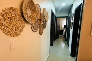 A hallway with decorative wall hangings and a light switch.