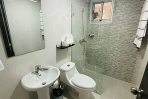 A bathroom with a glass-enclosed shower, a sink, and a toilet. - Moderno, Seguro, Cerca Aeropuerto SDQ, Gym, 2 Parqueos (Santo Domingo Este)