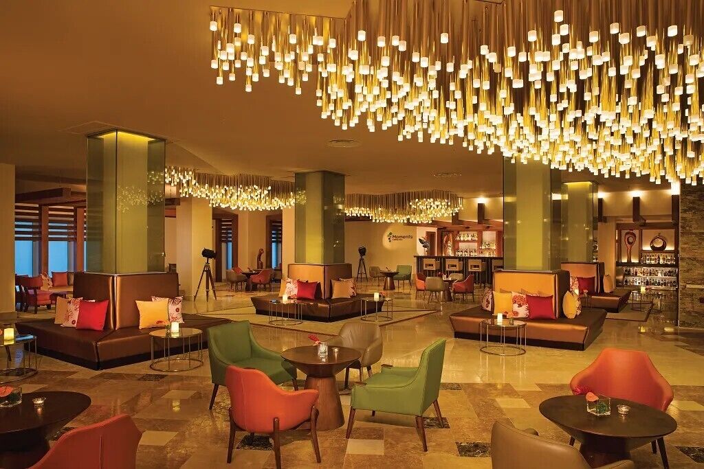 Een hotel lobby met zithoeken, een bar en een grote kroonluchter.