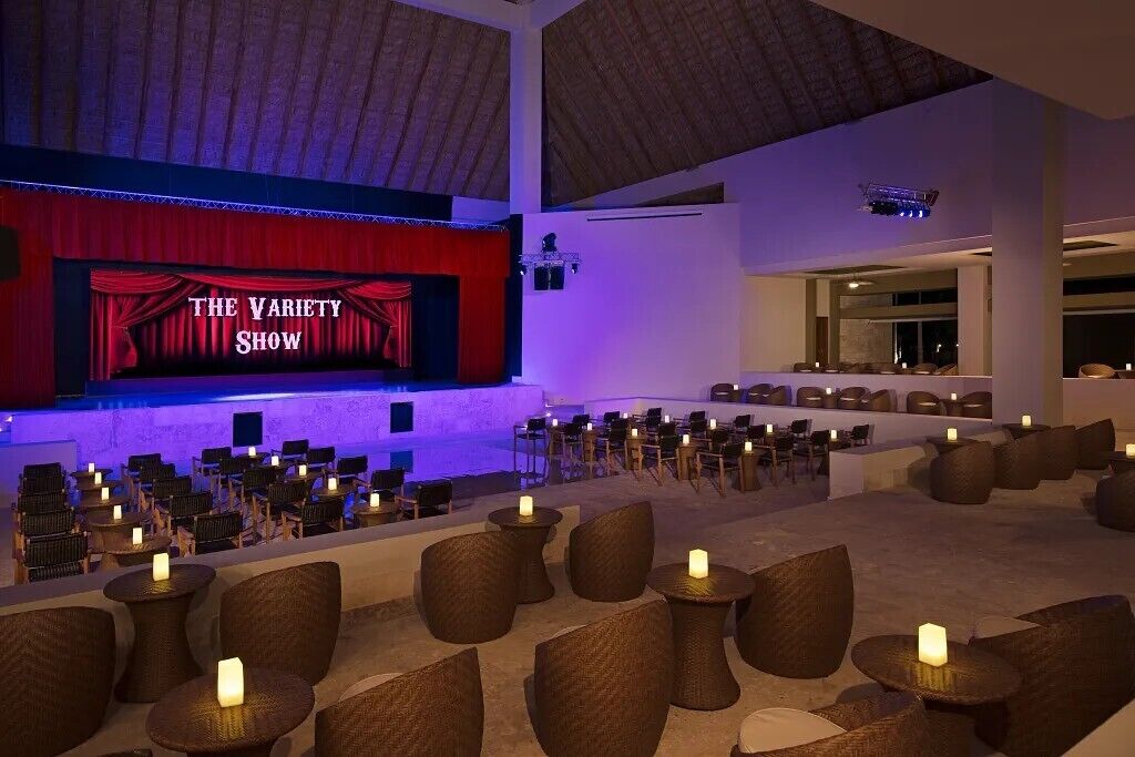 Un teatro con un escenario que muestra el letrero 'THE VARIETY SHOW' y filas de asientos.