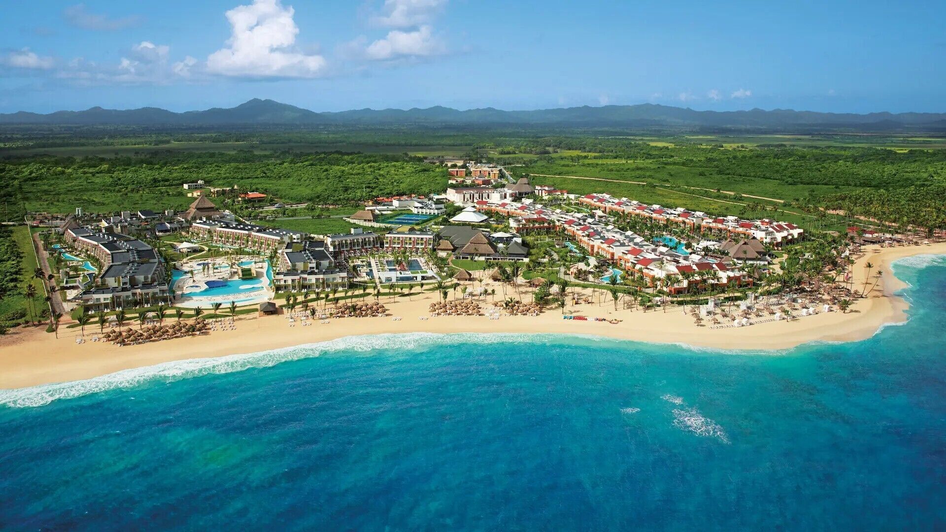 Een resort met meerdere gebouwen, een strand en een zwembad.