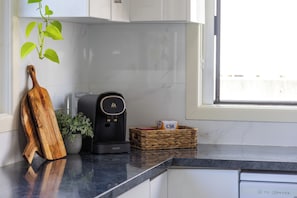 A kitchen with a coffee maker, a wooden cutting board, a potted plant, and a basket with a box labeled 'CSR'. - Ocean Views - 300m to Beach - 3km to Big Banana (Korora)