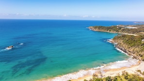 A coastal landscape with a beach, clear blue sea, and a hilly terrain. - Ocean Views - 300m to Beach - 3km to Big Banana (Korora)