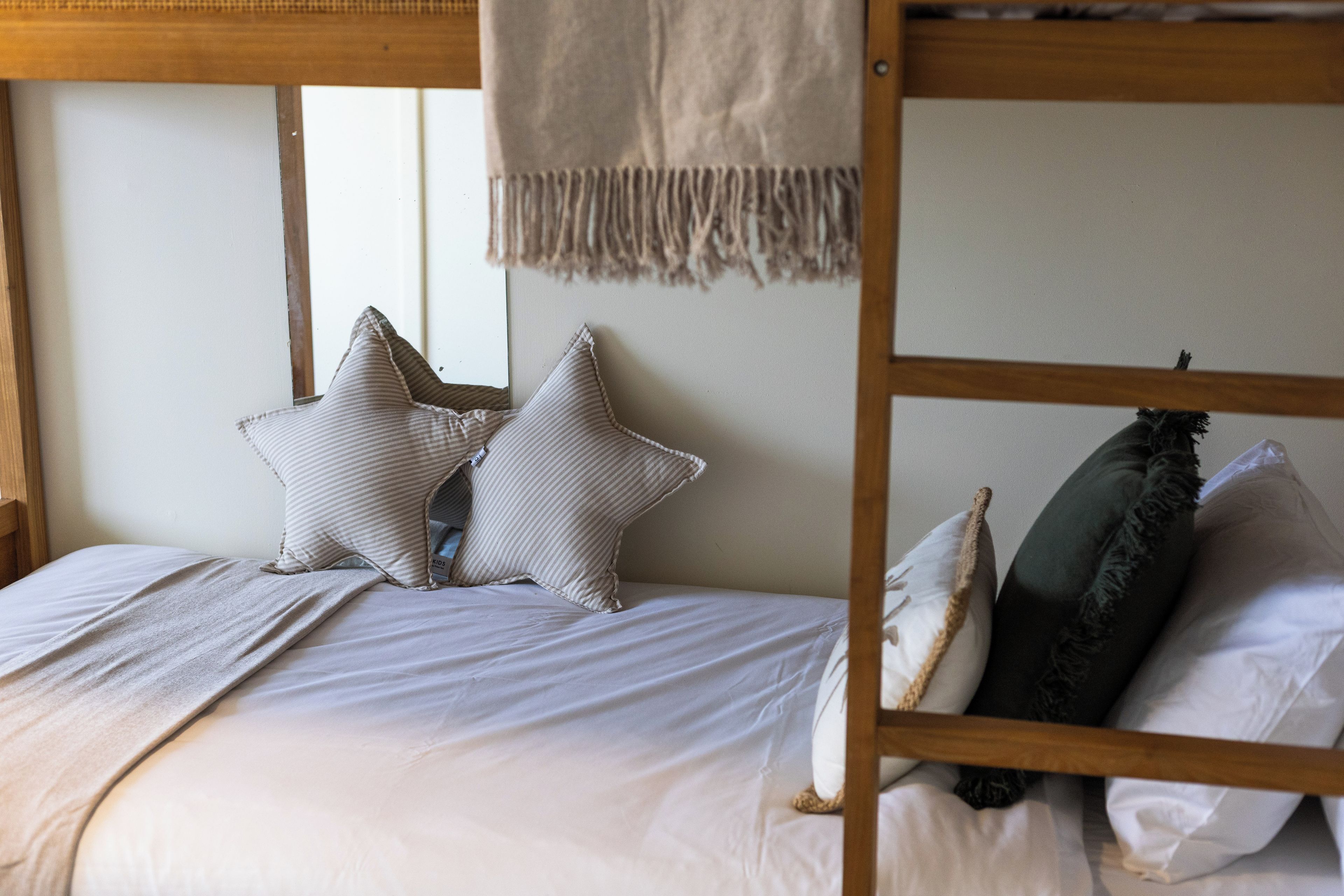 Una cama individual con cabecera, dos almohadas, una colcha y un adorno colgante de macramé.