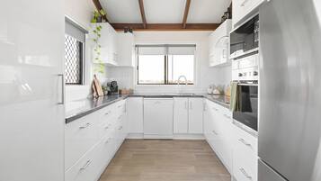 A modern kitchen with white cabinetry, a stainless steel refrigerator, and a window above the sink.