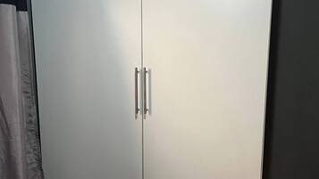 A large wardrobe with two doors and handles, a wooden floor, and a curtain partially visible.