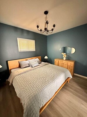 A bedroom with a bed, a nightstand, a dresser, a mirror, and a chandelier. - Brand New Stunning Home 3 min to Niagara Falls (Niagara Falls)