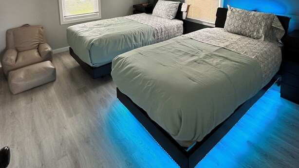 A bedroom with two beds, a chair, and a ceiling light fixture.