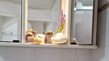 A bathroom with a white sink, a mirror above it, and a window with a view of the outside.