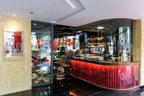 A modern interior with a curved counter, glass doors, and a view of the street outside. - IMPERIAL JADE SUITE at THE ONE SAIGON (Ho Chi Minh City)