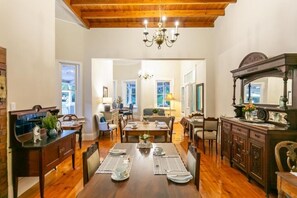 A dining area with a wooden table set for four, flanked by chairs, a dark wooden cabinet, and a large mirror. - Ostrich Baron's Palace (Oudtshoorn)
