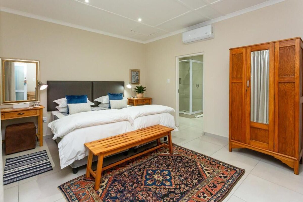 A bedroom with a bed, bedside table, lamp, and a large wardrobe.