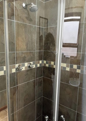 A shower with a glass door, tiled walls, and a corner tile design. - Room-charming Double Room Rental in Cape (Cape Town)