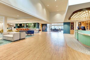 Eine großzügige Lobby mit Empfangsschalter, Sitzgelegenheiten und einer Bar.