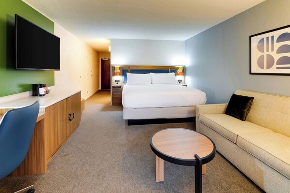 Ein Hotelzimmer mit Bett, einer Couch, einem Schreibtisch und einem Fernseher.