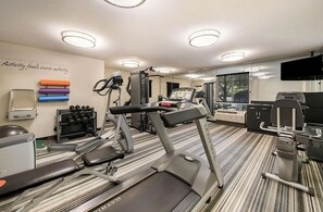 Ein Fitnessstudio mit Laufbändern, Kraftgeräten und Kurzhanteln.
