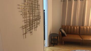 A room with a brown leather sofa, a patterned rug, and a wall-mounted abstract art piece.