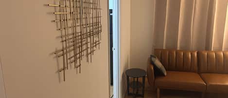 Una habitación con un sofá de cuero marrón, un tapete estampado y una obra de arte abstracta colgada en la pared.