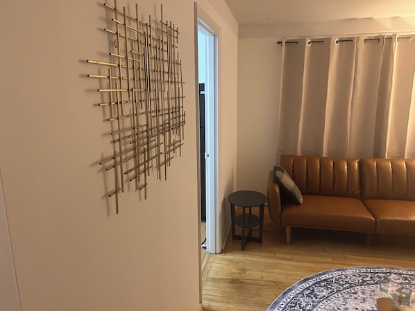 A room with a brown leather sofa, a patterned rug, and a wall-mounted abstract art piece.