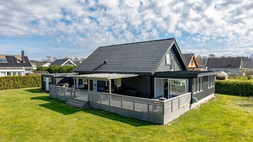 A modern house with a sloped roof, a covered patio, and a well-maintained lawn.
