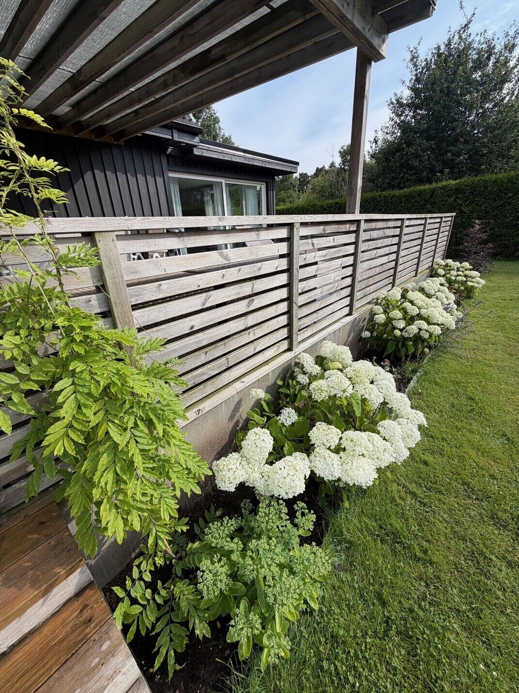 A wooden fence with white flowers and green foliage.