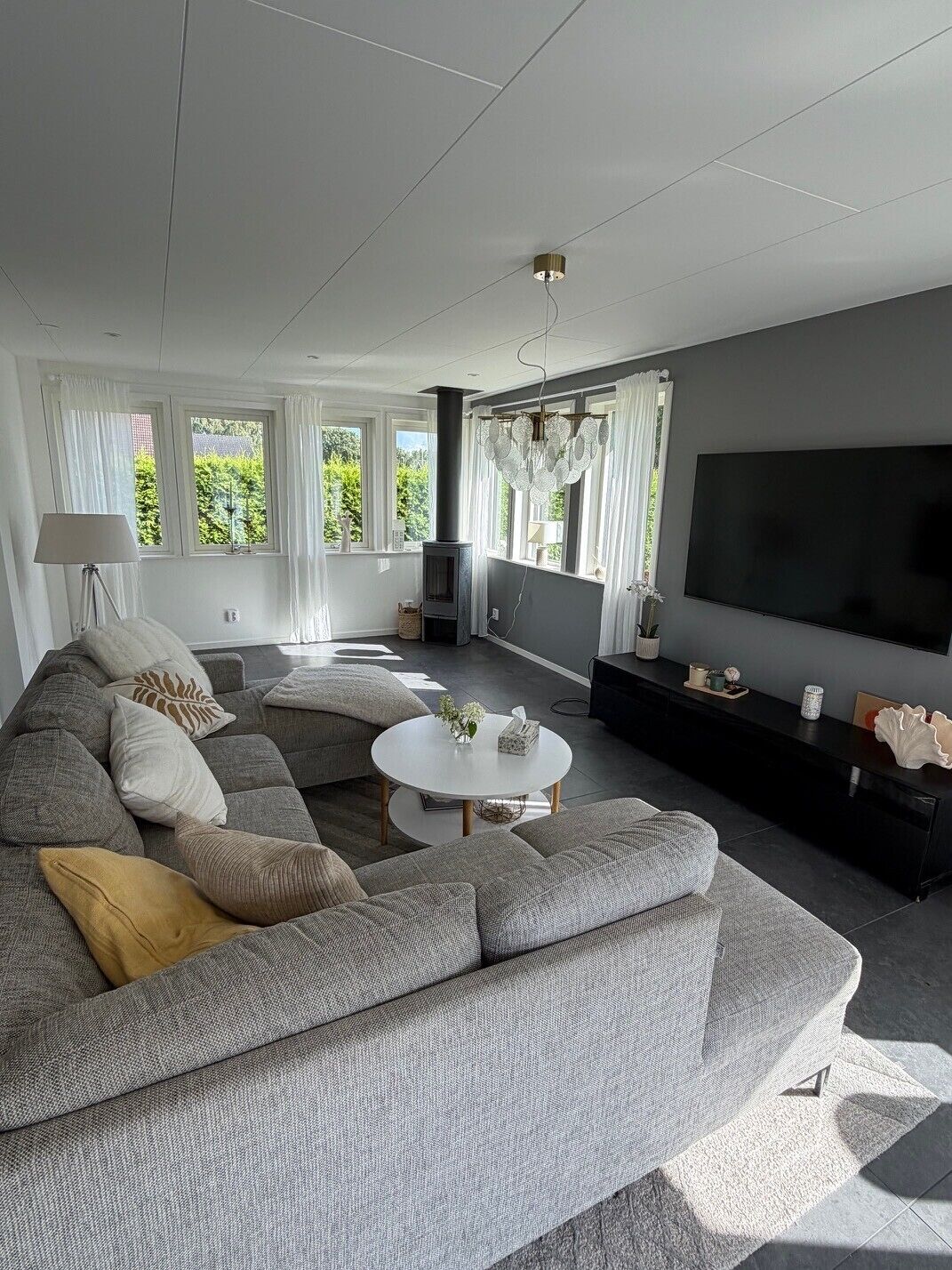 Ein modernes Wohnzimmer mit Ecksofa, Flachbildfernseher und Kamin.