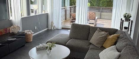 Ein modernes Wohnzimmer mit einem Ecksofa, einem runden Couchtisch und einem Fernseher.