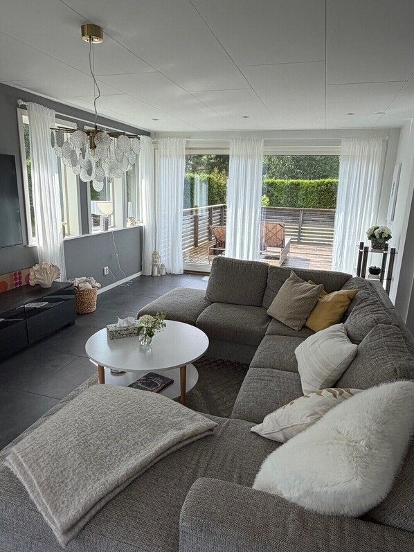 A modern living room with a sectional sofa, a round coffee table, and a television.