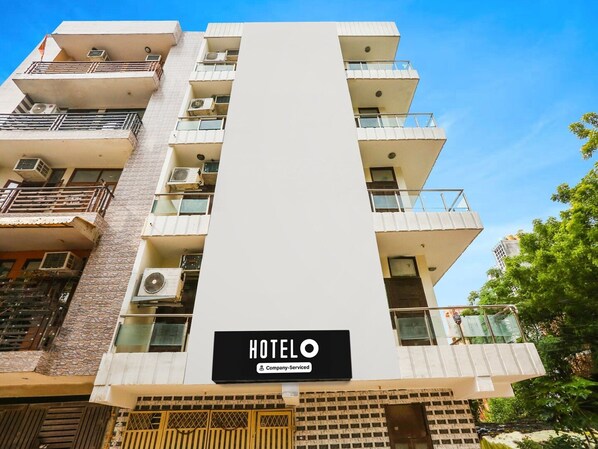 A multi-story hotel with balconies, air conditioning units, and a sign indicating it is company-serviced.