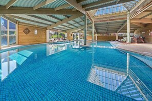 An indoor swimming pool with clear water, a tiled floor, and a wooden interior. - Nilora Resorts & Hotels (Port Macquarie)