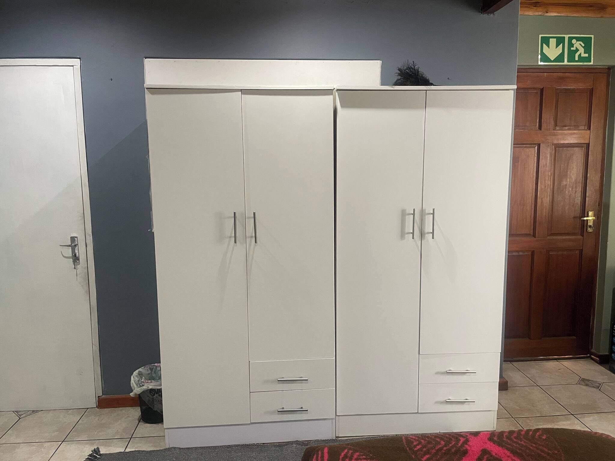 A room with a large white wardrobe, a wooden door, and a tiled floor.