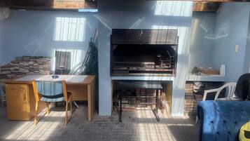 A patio area with a brick floor, a wooden table with chairs, a blue sofa, and a fireplace.