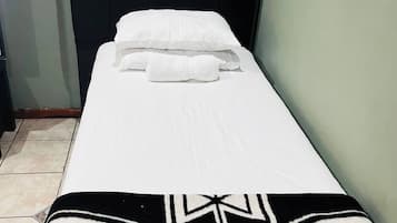 A single bed with white bedding and a black and white patterned blanket.