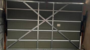 A garage with a metal door and a brick floor.