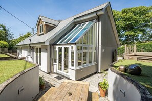 A modern house with a sloped roof, large windows, and a wooden deck. - Avalon Beach House - sleeps 6 guests  in 3 bedrooms (Falmouth)