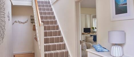 A staircase with a striped carpet, a white wall with a framed picture, and a radiator.