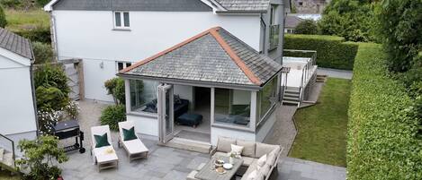 Una casa moderna con patio amueblado, jacuzzi y porche con cerramiento de vidrio.