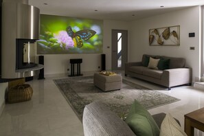 En moderne stue med et fladskærms-tv, en sofa, et sofabord og en dekorativ vægdekoration.