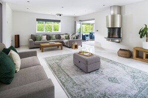 A modern living room with a sofa set, a coffee table, a rug, and a fireplace. - Bryher Garden - sleeps 8 guests  in 4 bedrooms (Penzance)