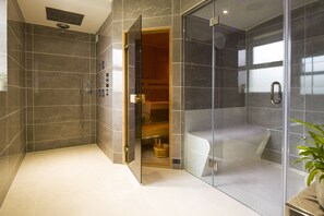 Ein modernes Badezimmer mit einer gläsernen Dusche, einer Holzbank und einem sichtbaren Stauraum.