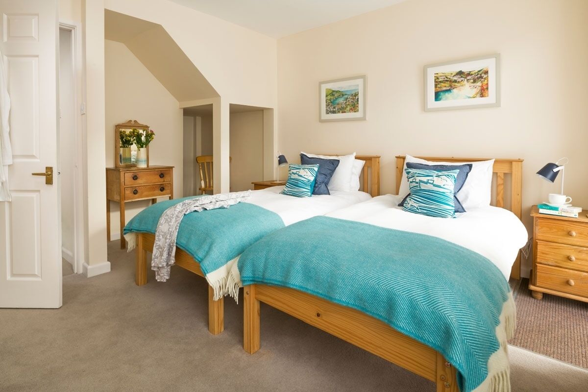 A bedroom with two beds, a dresser, a nightstand, and a door.