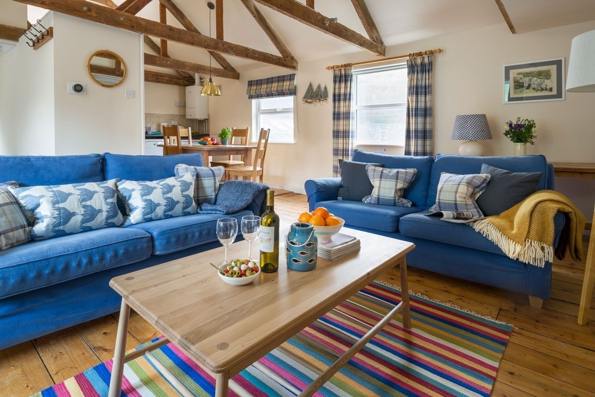 Un salon avec deux canapés bleus, une table basse en bois et un tapis rayé aux couleurs vives.