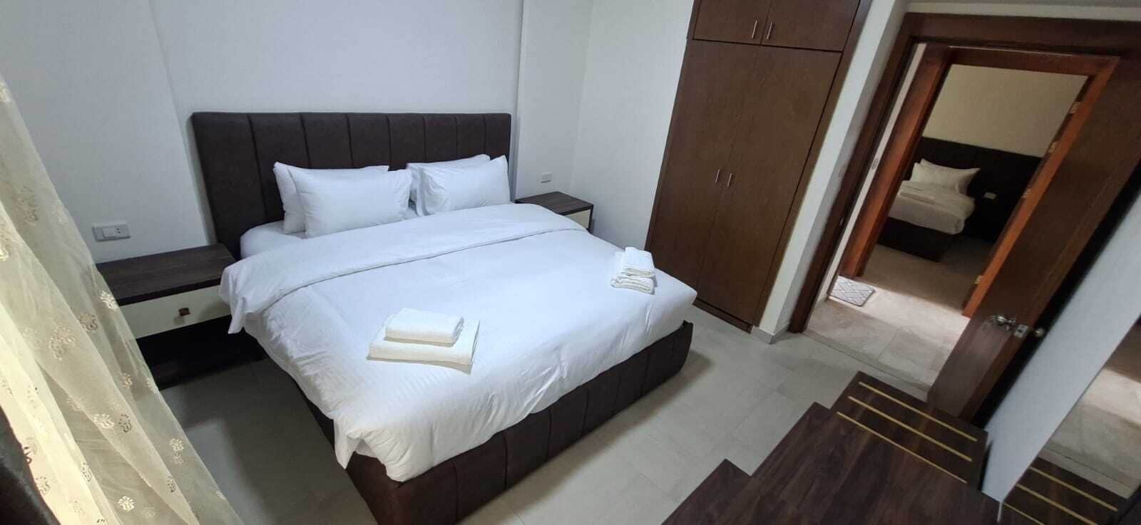 Una habitación de hotel con una cama, una mesita de noche, un armario y un espejo.