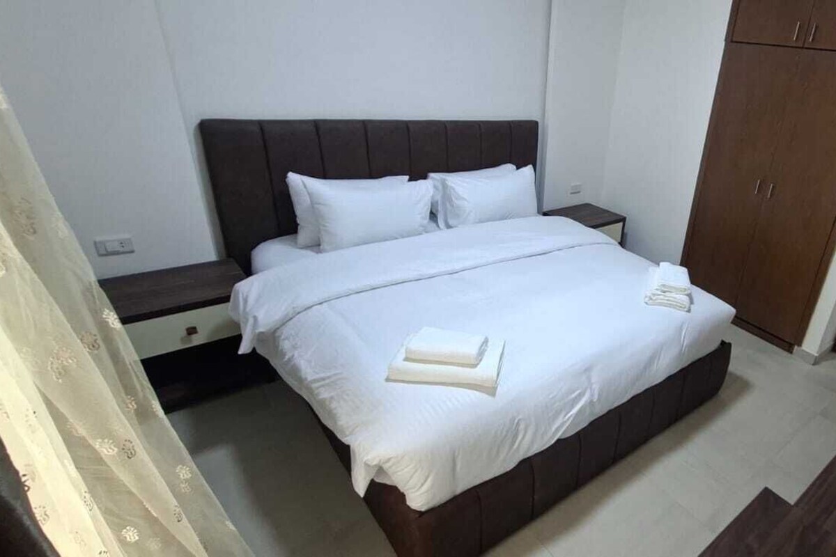 A hotel room with a bed, a nightstand, a wardrobe, and a mirror.