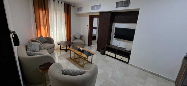 A living room with a sofa, armchairs, a coffee table, a TV, and a TV stand. - Beity Rose (Amman)