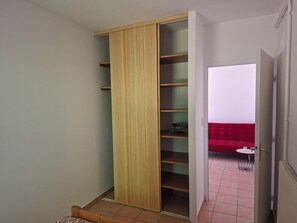 Une pièce avec une armoire en bois, un canapé rouge et une petite table sur laquelle se trouve un panier.