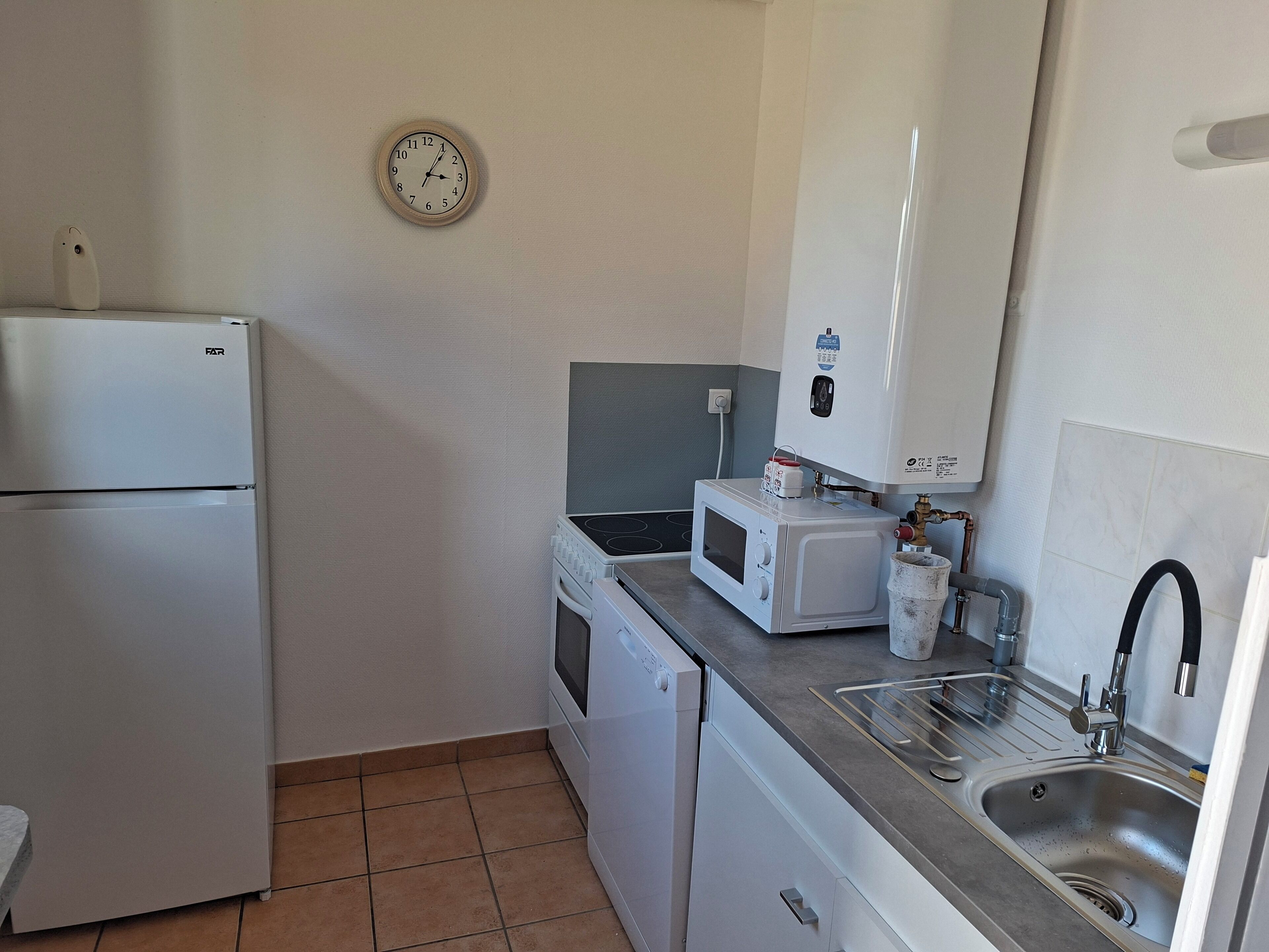 Een kleine keuken met een koelkast, magnetron en vaatwasser.