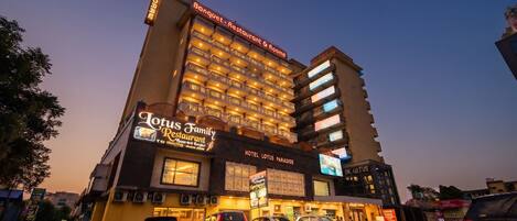 Un hôtel à plusieurs étages, un restaurant appelé « Lotus Family Restaurant » et une enseigne indiquant « Banquet – Restaurant et chambres ».