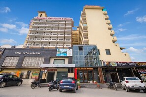 A hotel with multiple floors, balconies, and a variety of shops on the ground level. - Hotel Lotus Paradise By Golden Key  (Sonepat)